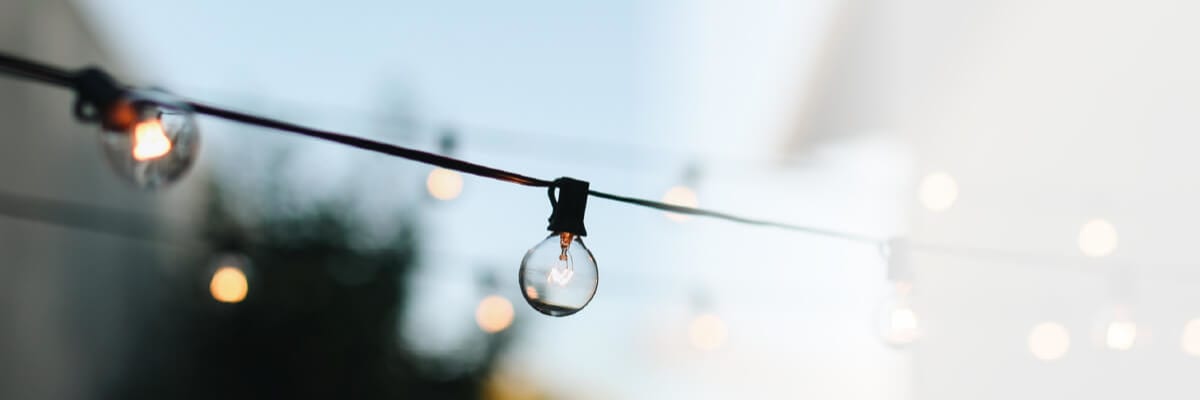 Close-up of round string lights hanging outdoors with a soft focus background during early evening.