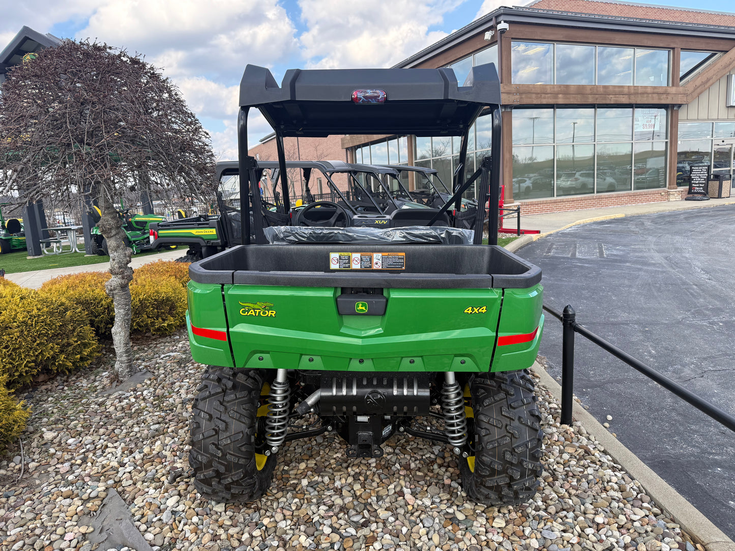 Rear view of a green John Deere utility vehicle with 4x4 capability parked on gravel outside a commercial building at Hartville Hardware.