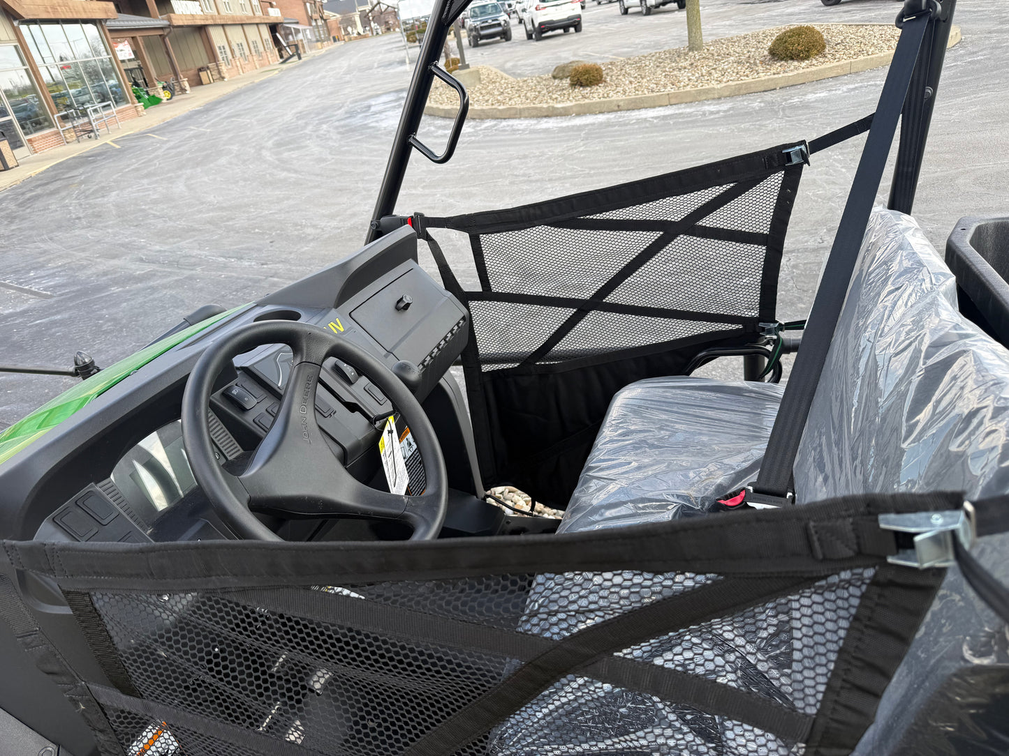 Interior view of a green mid-size utility vehicle showing steering wheel, dashboard controls, and mesh safety netting at Hartville Hardware.
