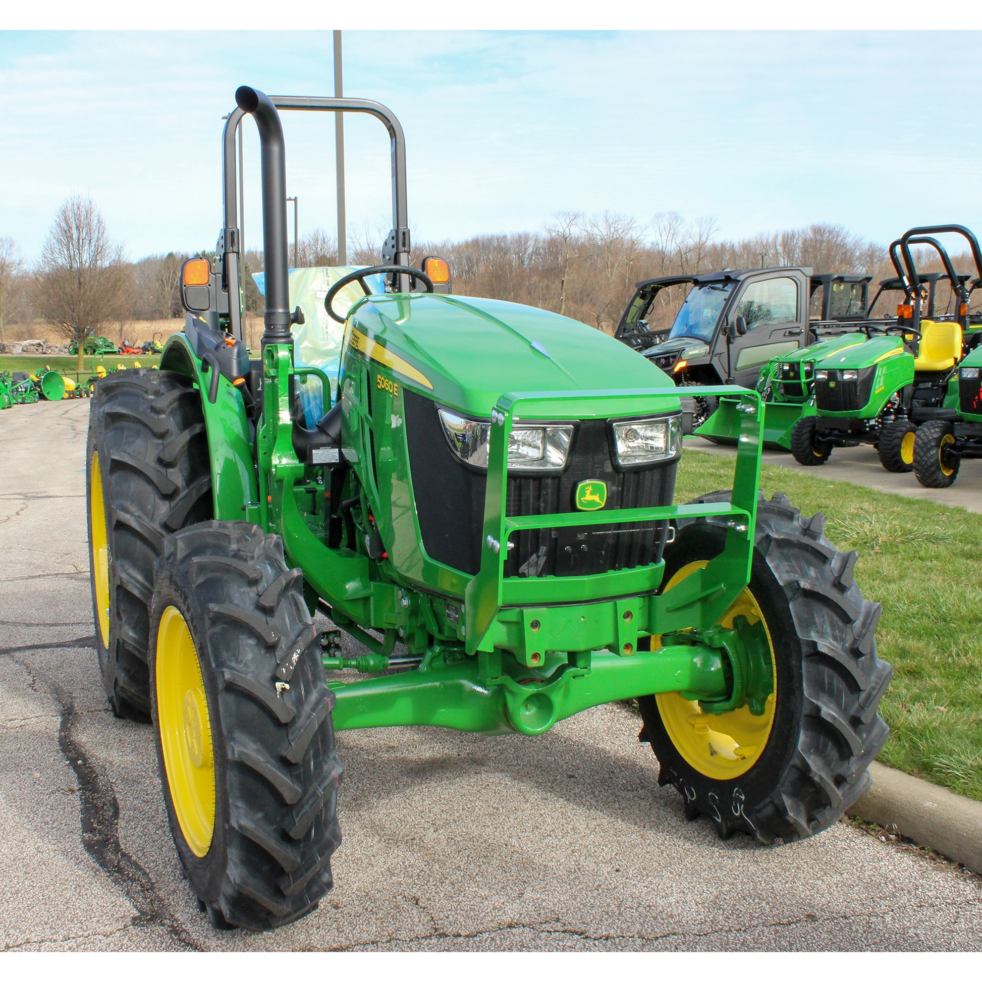 Green utility tractor with yellow wheels and protective roll bar parked on pavement outdoors at Hartville Hardware in the John Deere Products collection.