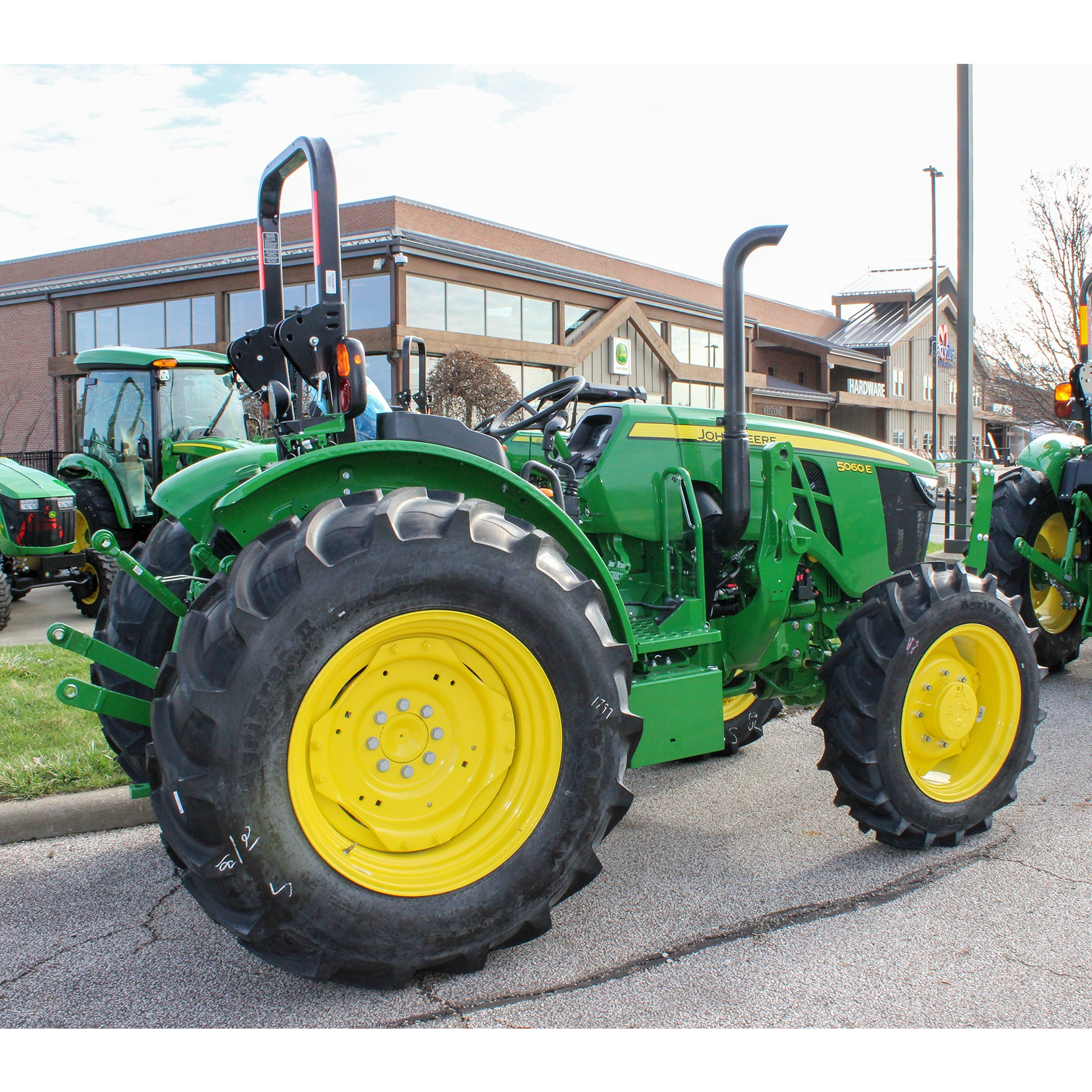 Green John Deere 5060E utility tractor with yellow wheels parked outdoors at Hartville Hardware in the John Deere Products section.