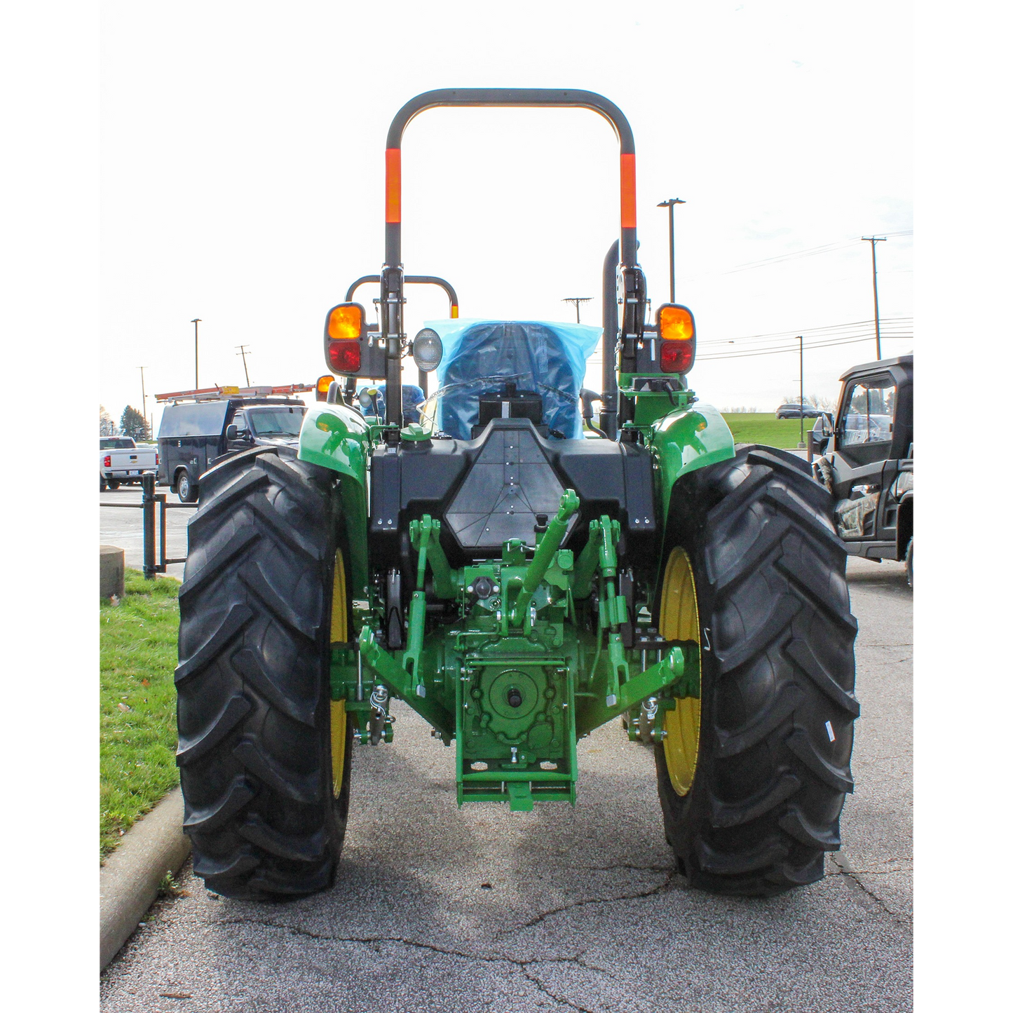 Rear view of a green utility tractor with large textured tires and safety lights, displayed outdoors at Hartville Hardware in the John Deere Products section.