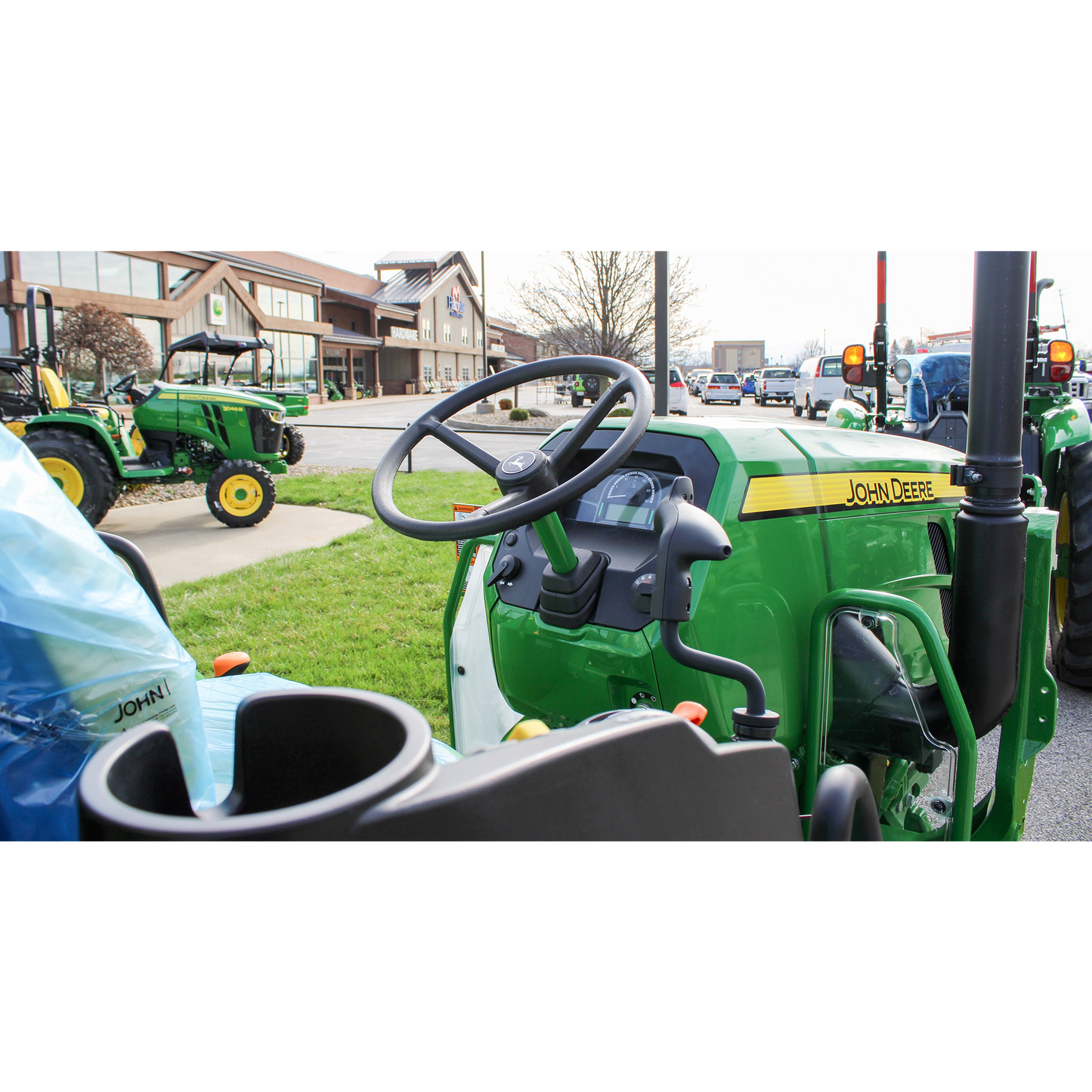 Close-up of the steering wheel and dashboard on a green John Deere 5060E utility tractor displayed outdoors at Hartville Hardware in the John Deere Products section.