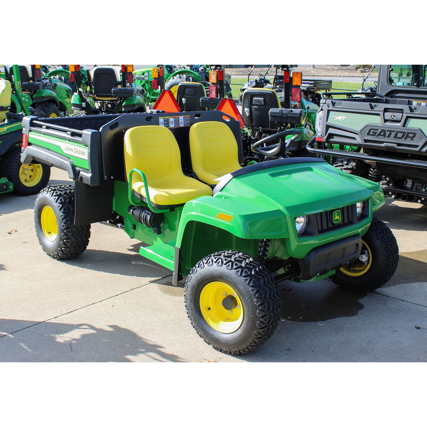 Green John Deere utility vehicle with yellow seats and rugged tires, displayed outdoors at Hartville Hardware in the John Deere UTVs and equipment section.