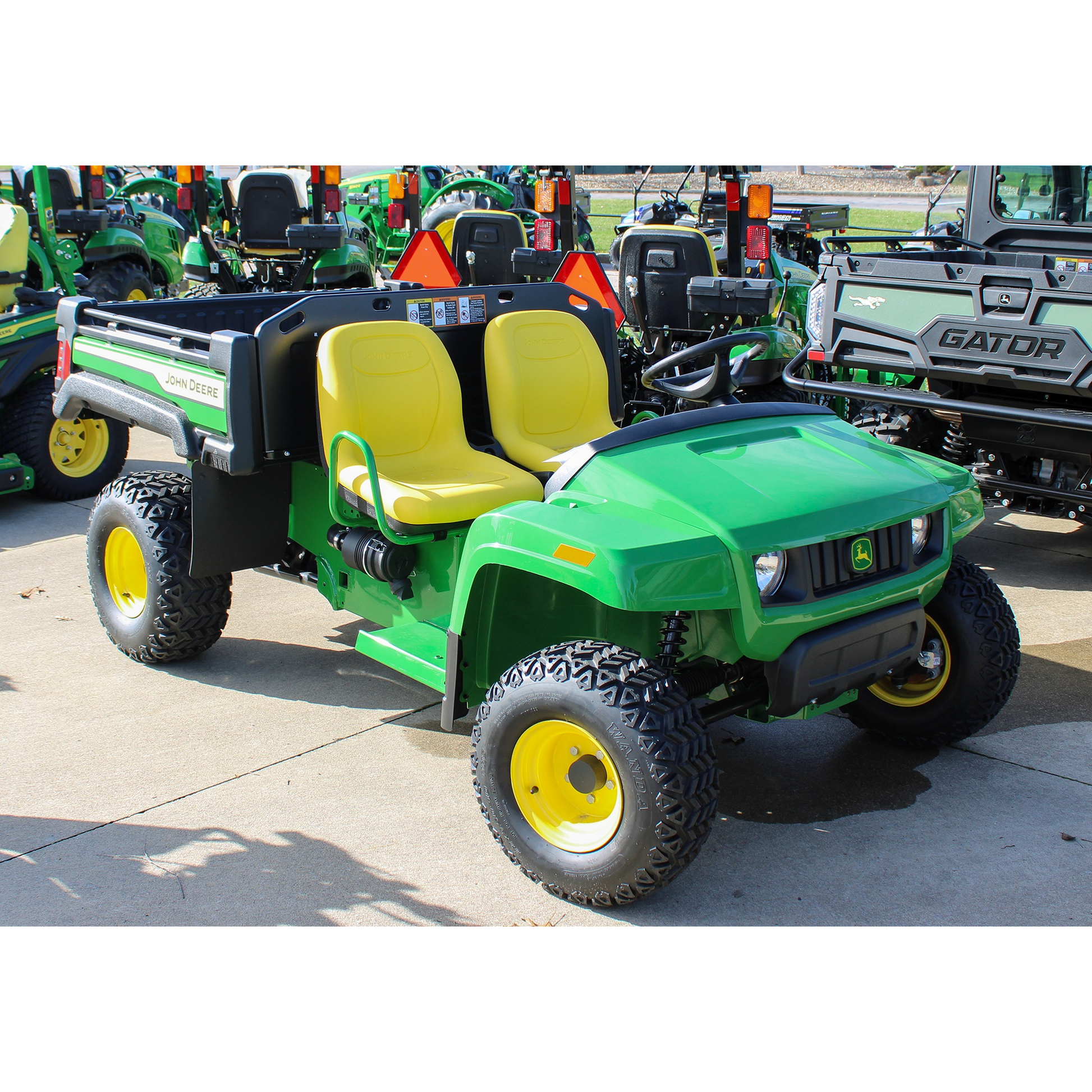Green John Deere utility vehicle with yellow seats and rugged tires, displayed outdoors at Hartville Hardware in the John Deere UTVs and equipment section.