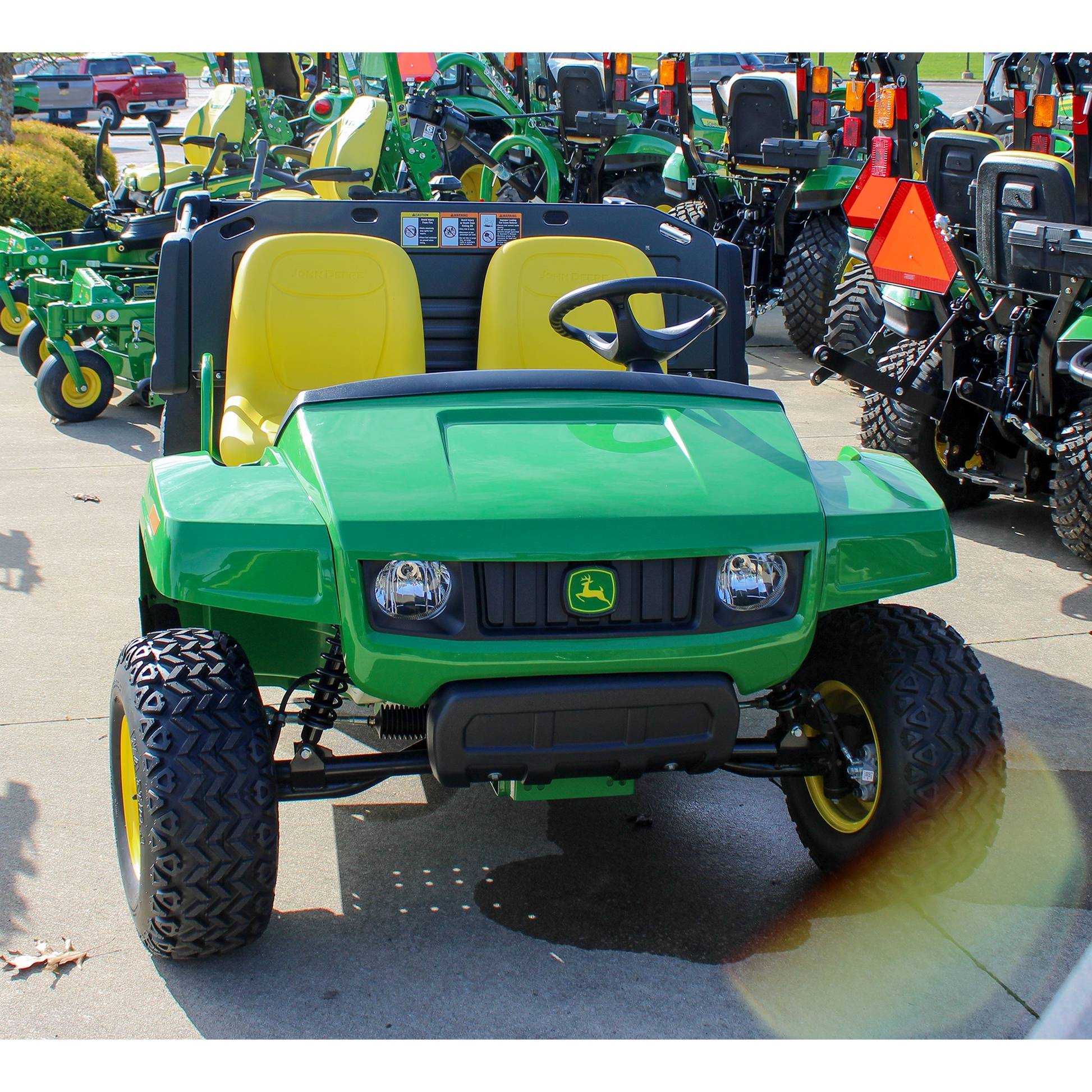 Green John Deere utility vehicle with dual yellow seats and rugged off-road tires, displayed outdoors at Hartville Hardware in the UTVs section.