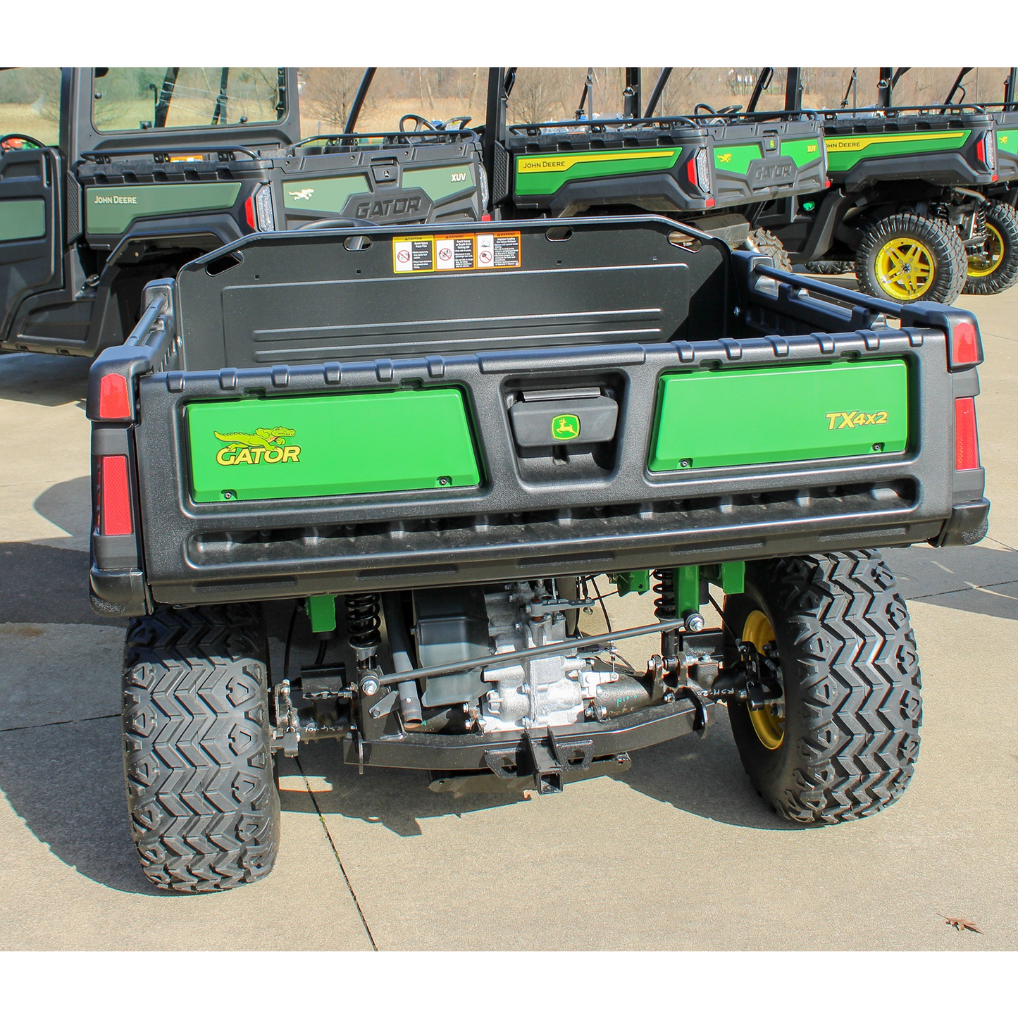Rear view of a John Deere utility vehicle showcasing rugged tires, suspension, and cargo bed, displayed outside Hartville Hardware in John Deere UTVs section.