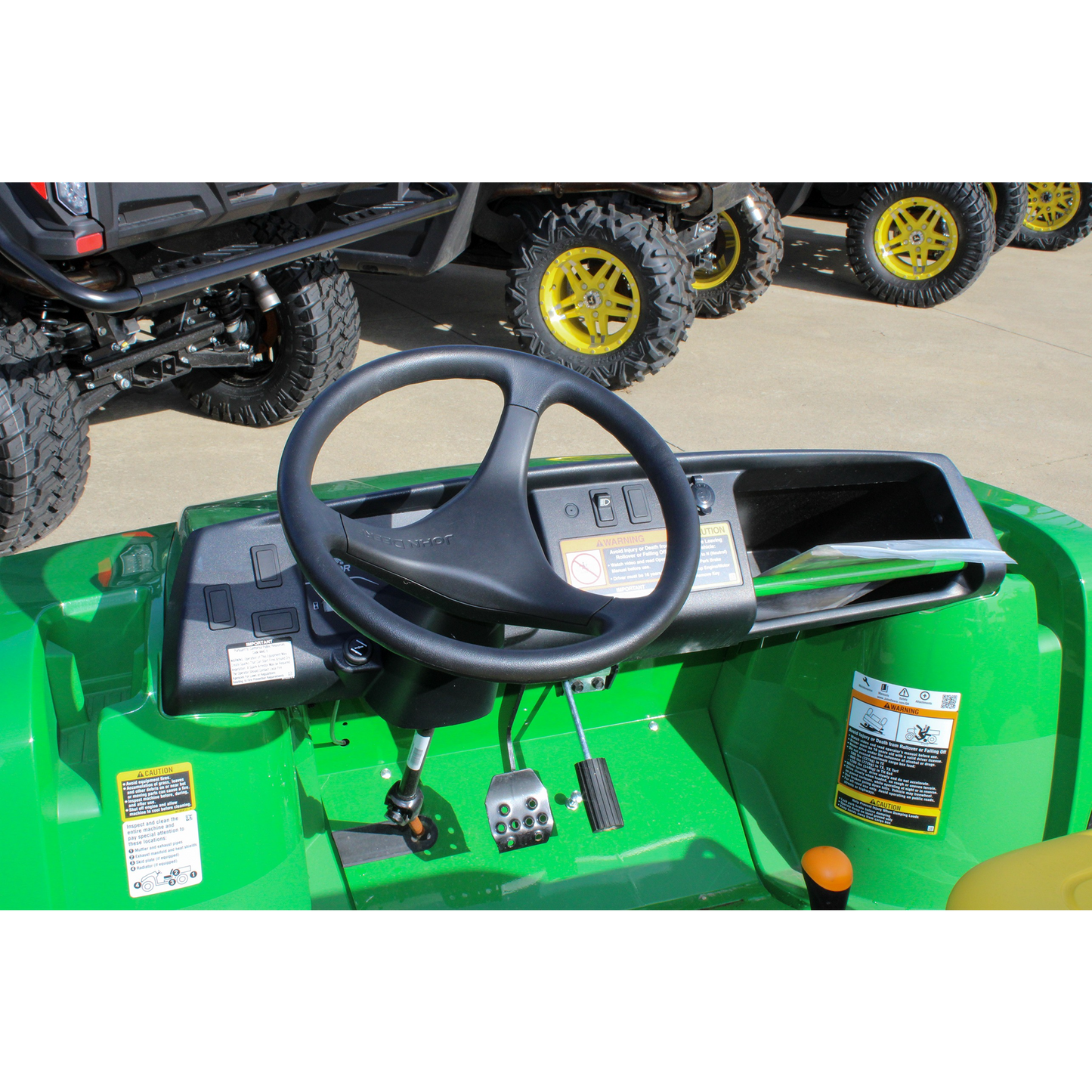Dashboard and steering wheel view of a green John Deere utility vehicle featuring pedals and control panel, shown at Hartville Hardware in UTVs section.