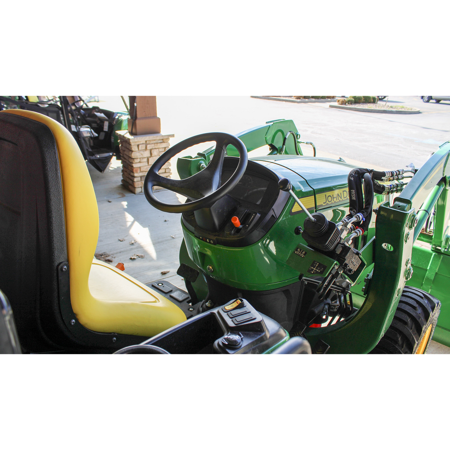 Operator seat and control panel of a green John Deere compact utility tractor displayed outdoors at Hartville Hardware in the Outdoor Power Equipment section.