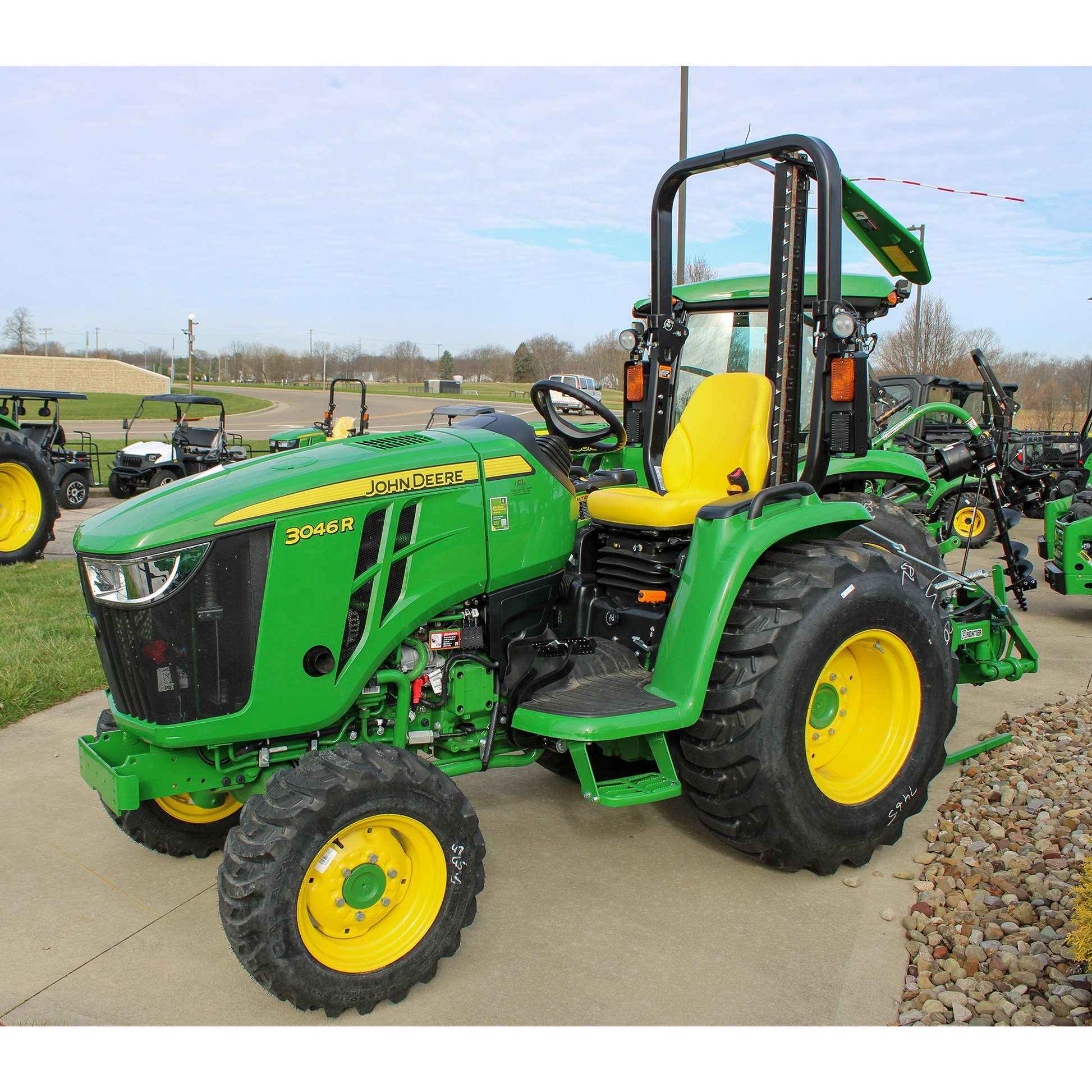 Green John Deere 3046R tractor with yellow seat and large rear tires, displayed outdoors in the Lawn & Garden section at Hartville Hardware among Outdoor Power Equipment and Tools.