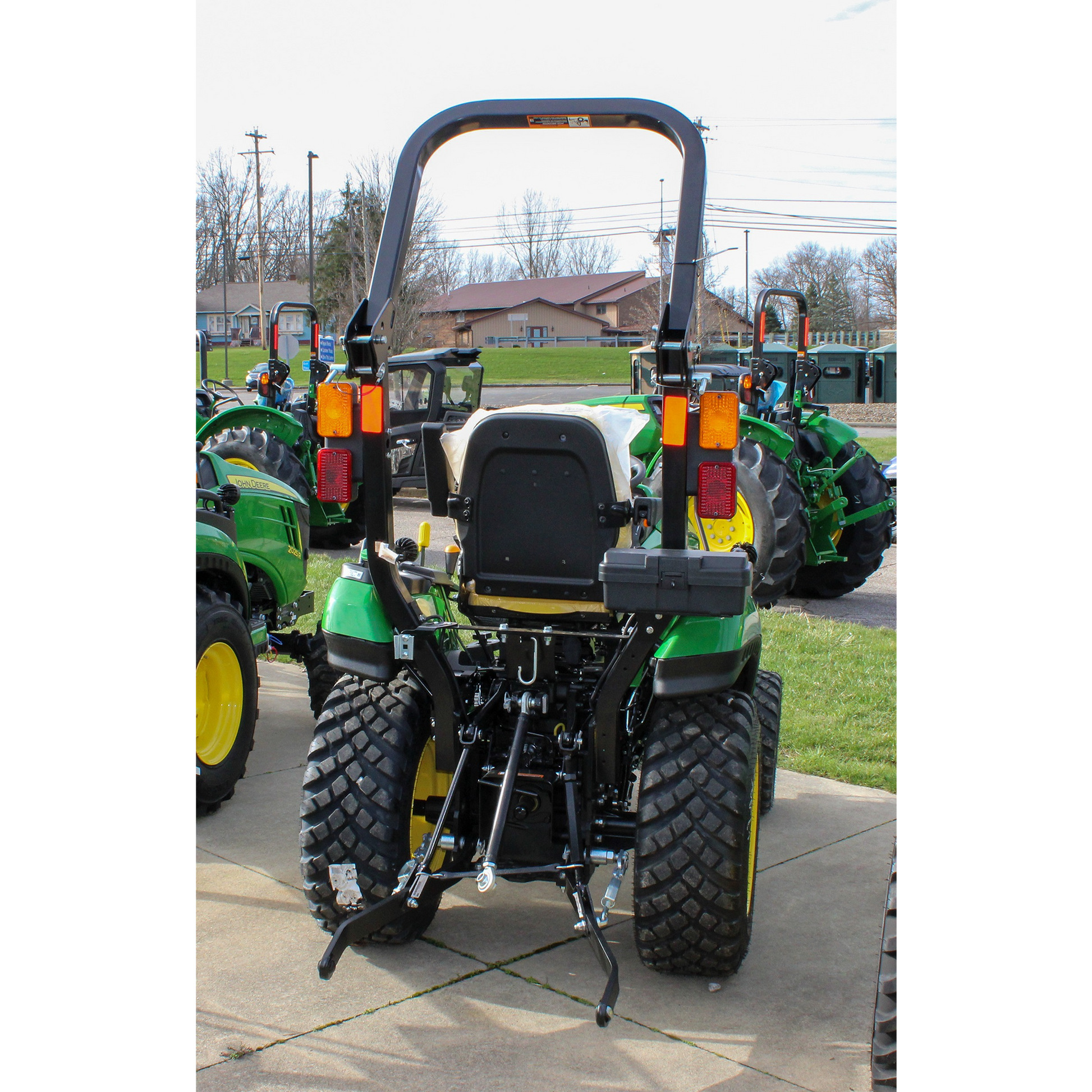 Rear view of a green compact tractor with large treaded tires, rollover protection bar, and hitch components, part of outdoor power equipment and lawn and garden tools collections.