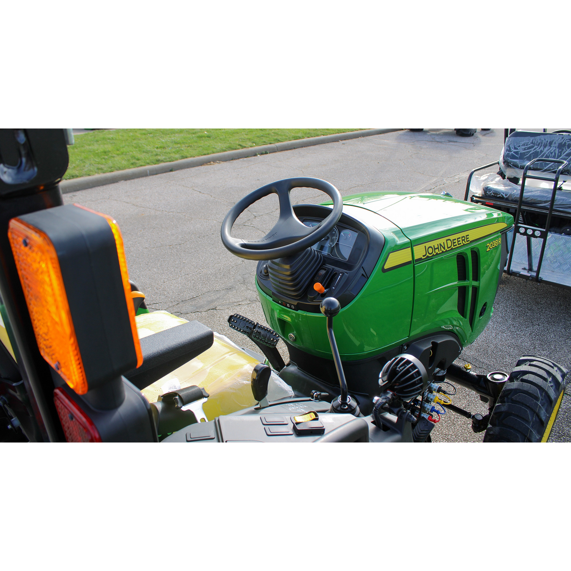 Close-up view of a green John Deere 2038R compact tractor dashboard and steering wheel, part of outdoor power equipment and lawn & garden collections.