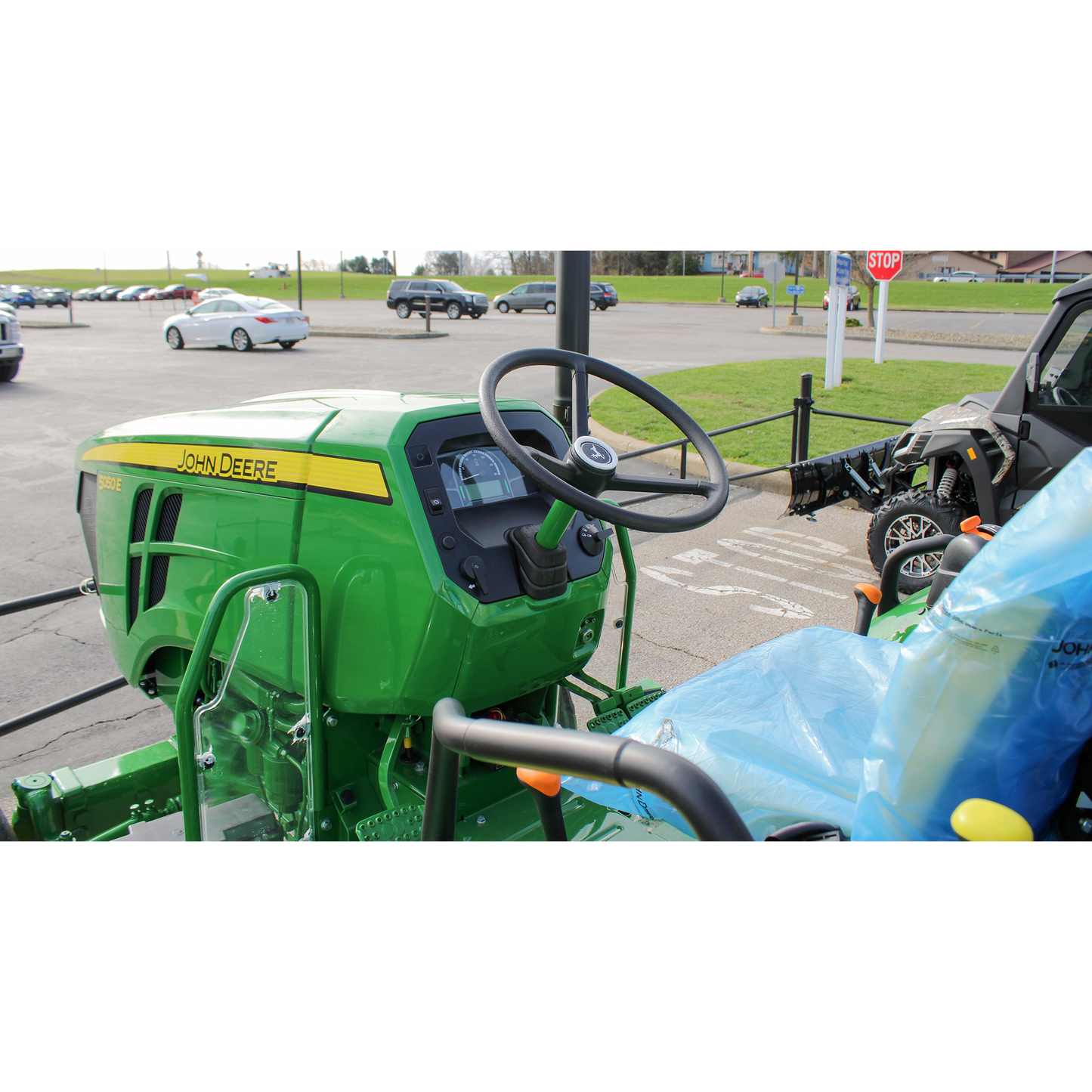 Green John Deere utility tractor featuring a steering wheel and control panel with the brand name displayed, shown outdoors at Hartville Hardware in the Outdoor Power Equipment section.