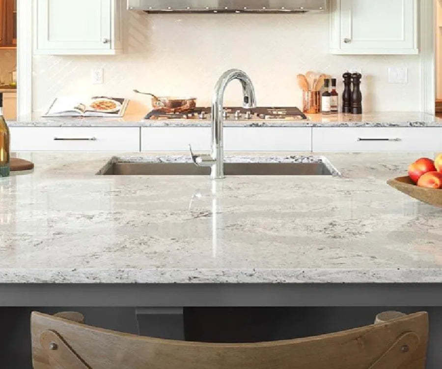 Spacious kitchen countertop with light gray and white marbling, featuring a modern chrome faucet and neutral-toned cabinetry in the background.