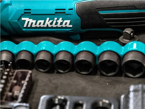 Close-up view of a blue and black cordless power tool with the brand name alongside a set of socket wrench attachments arranged on a dark surface.