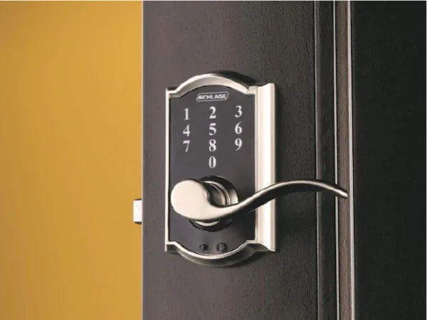 Electronic door lock with a keypad and curved metal handle mounted on a dark door against a yellow wall, highlighting home improvement features.