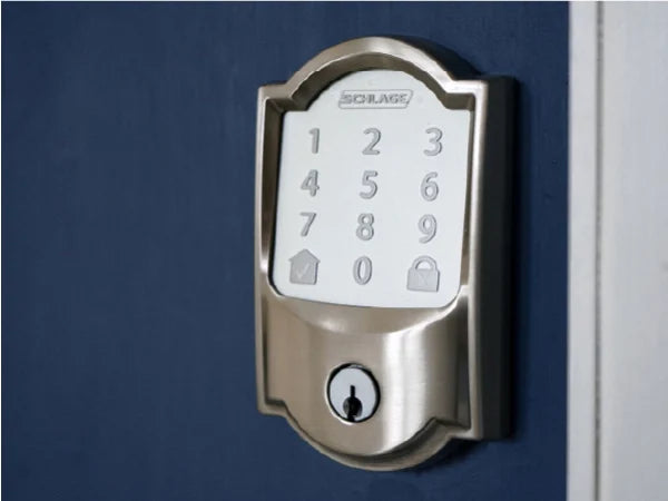 Keypad-style smart lock with brushed metal finish mounted on a dark blue door, featuring numeric buttons and a keyhole below.