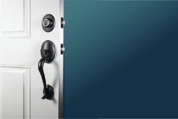 Close-up of a black metal door handle and deadbolt on a white door against a solid blue background, suggesting home improvement.