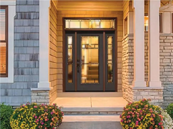 Front entrance featuring a dark-framed glass door with sidelights and transom, set within a welcoming porch highlighted by warm lighting and stone accents.