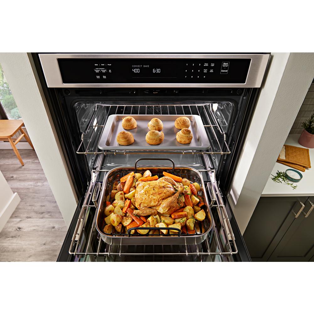 Combination microwave wall oven with roasted chicken, vegetables, and baked rolls inside kitchen setting