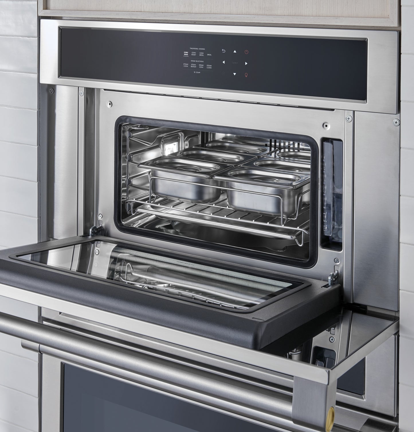 Built-in stainless steel steam oven with control panel and trays inside in modern kitchen appliances collection