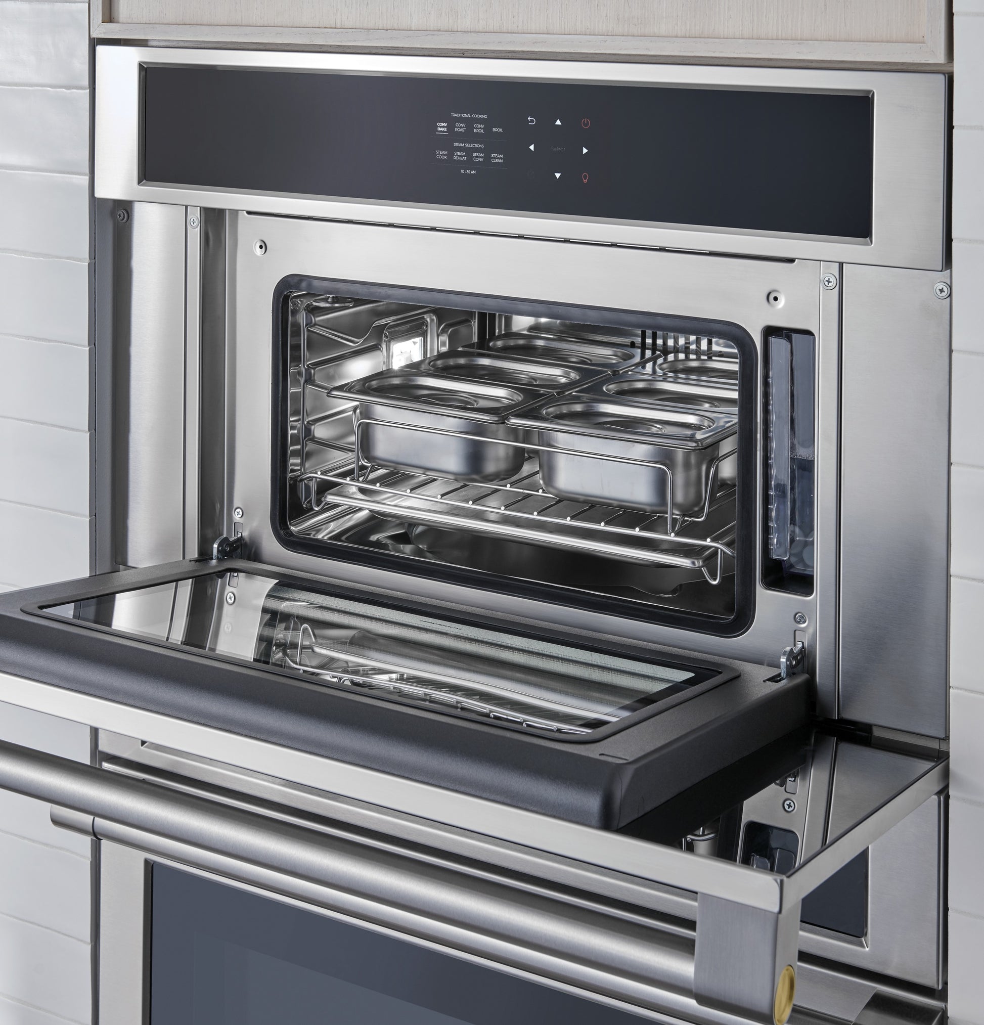 Built-in stainless steel steam oven with control panel and trays inside in modern kitchen appliances collection
