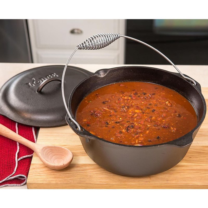 Cast iron Dutch oven with coil bail handle filled with chili stew on wooden board in kitchenware collection under $100