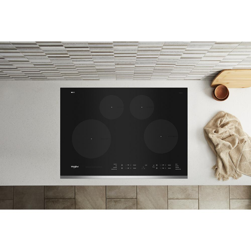 Black glass 30-inch induction cooktop with four cooking zones installed in modern kitchen countertop setting