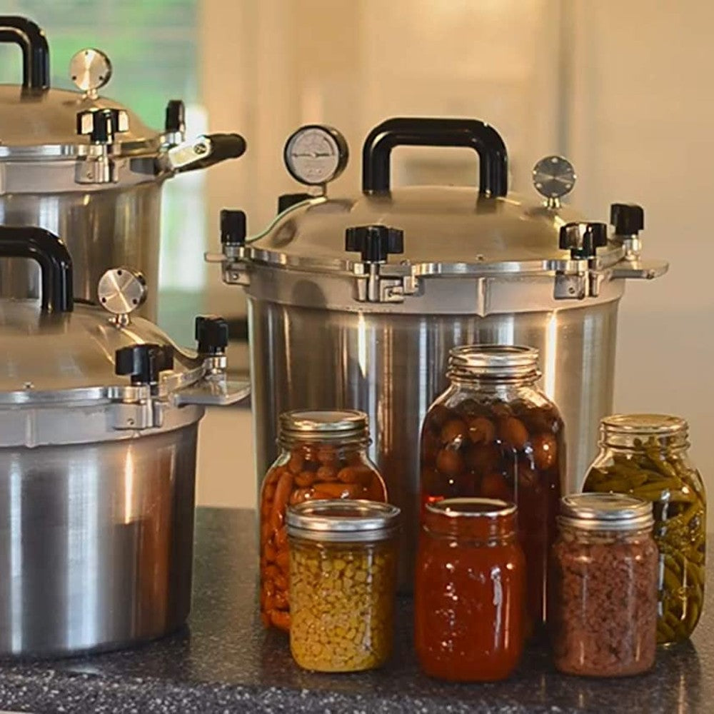Set of aluminum pressure canners with secure lids surrounded by assorted jars of preserved food in kitchenware collections