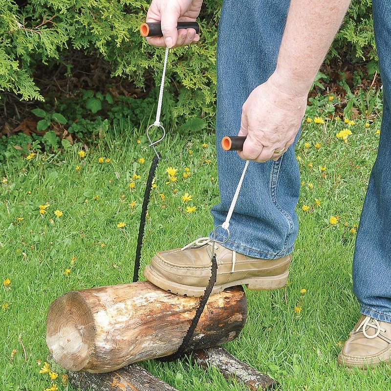 Person using compact pocket chainsaw with orange handles to cut a log outdoors in garden tools setting