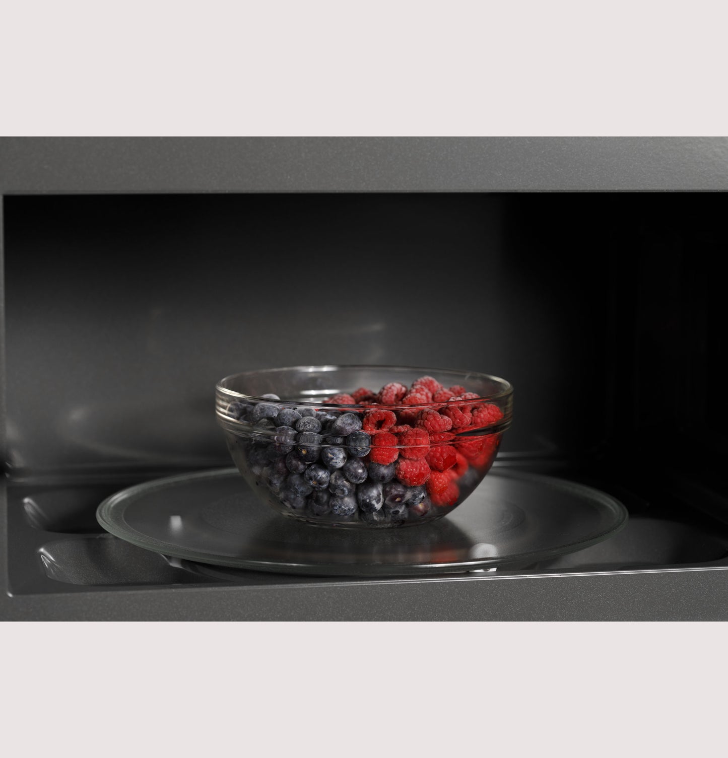 Glass bowl with fresh blueberries and raspberries inside microwave oven from kitchen and appliances collection