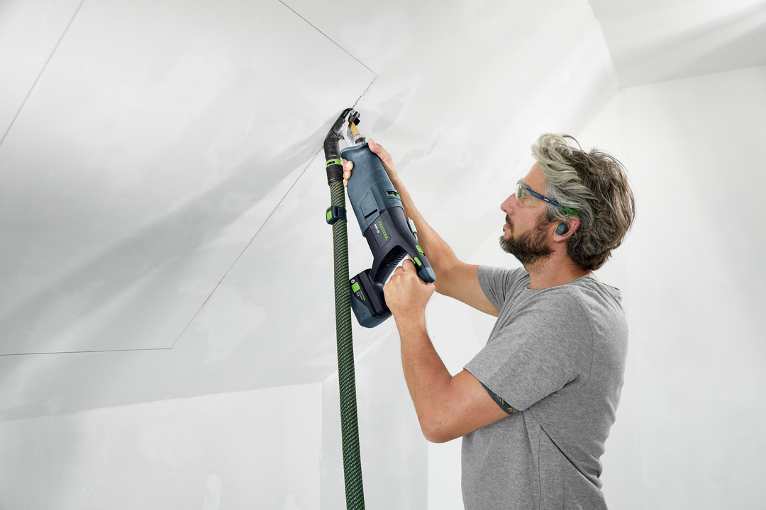 Man wearing safety glasses uses Festool 576950 RSC 18 EB-Basic cordless saw cutting drywall for home improvement project