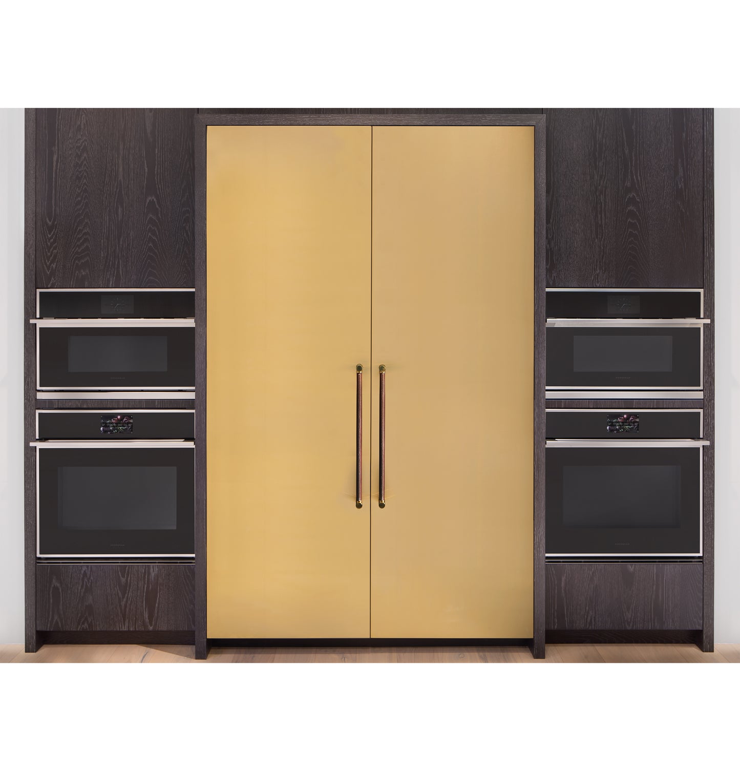 Built-in black ovens and microwaves flanking sleek gold minimalist double-door cabinetry in modern kitchen setting