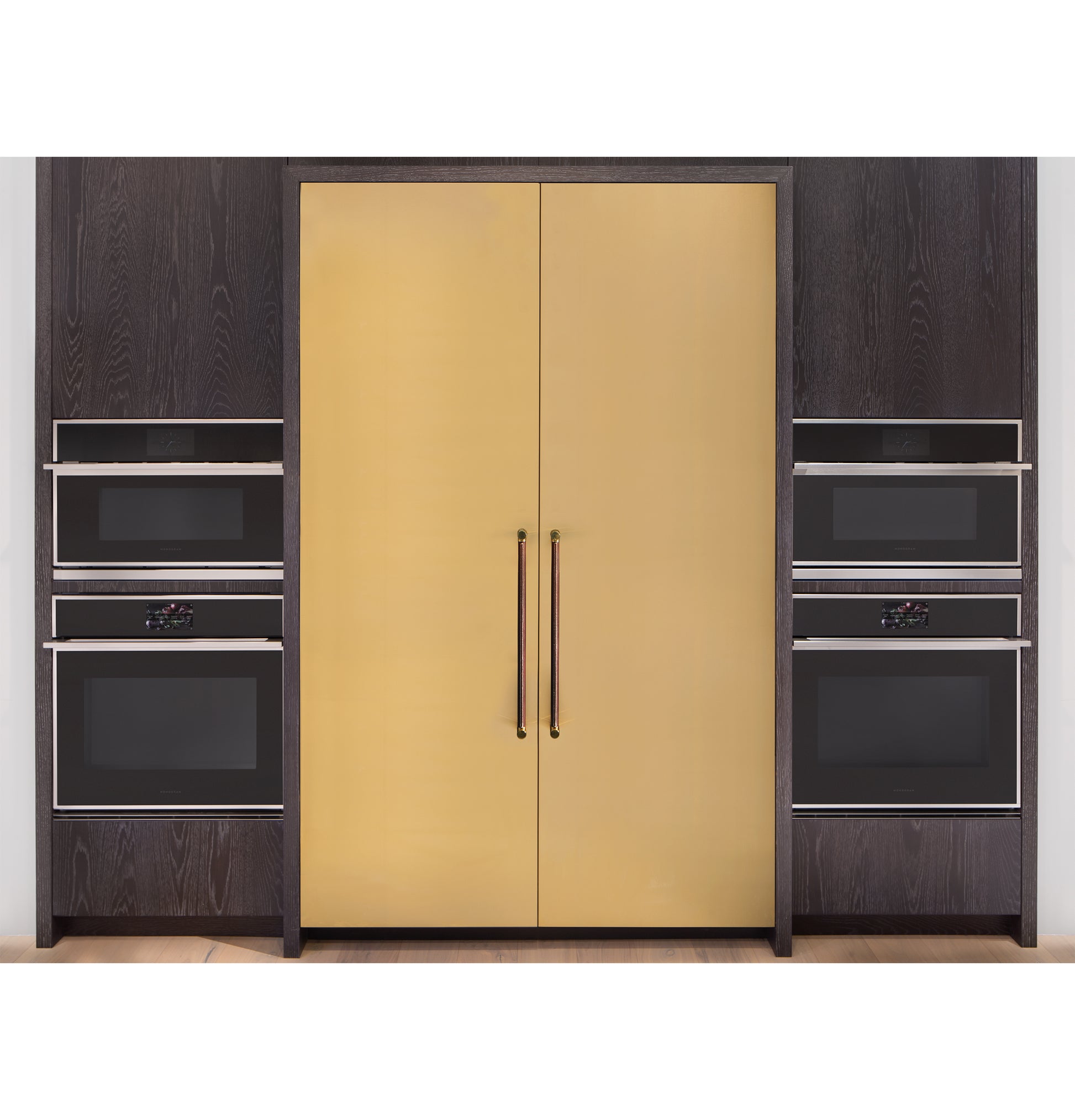 Built-in black ovens and microwaves flanking sleek gold minimalist double-door cabinetry in modern kitchen setting