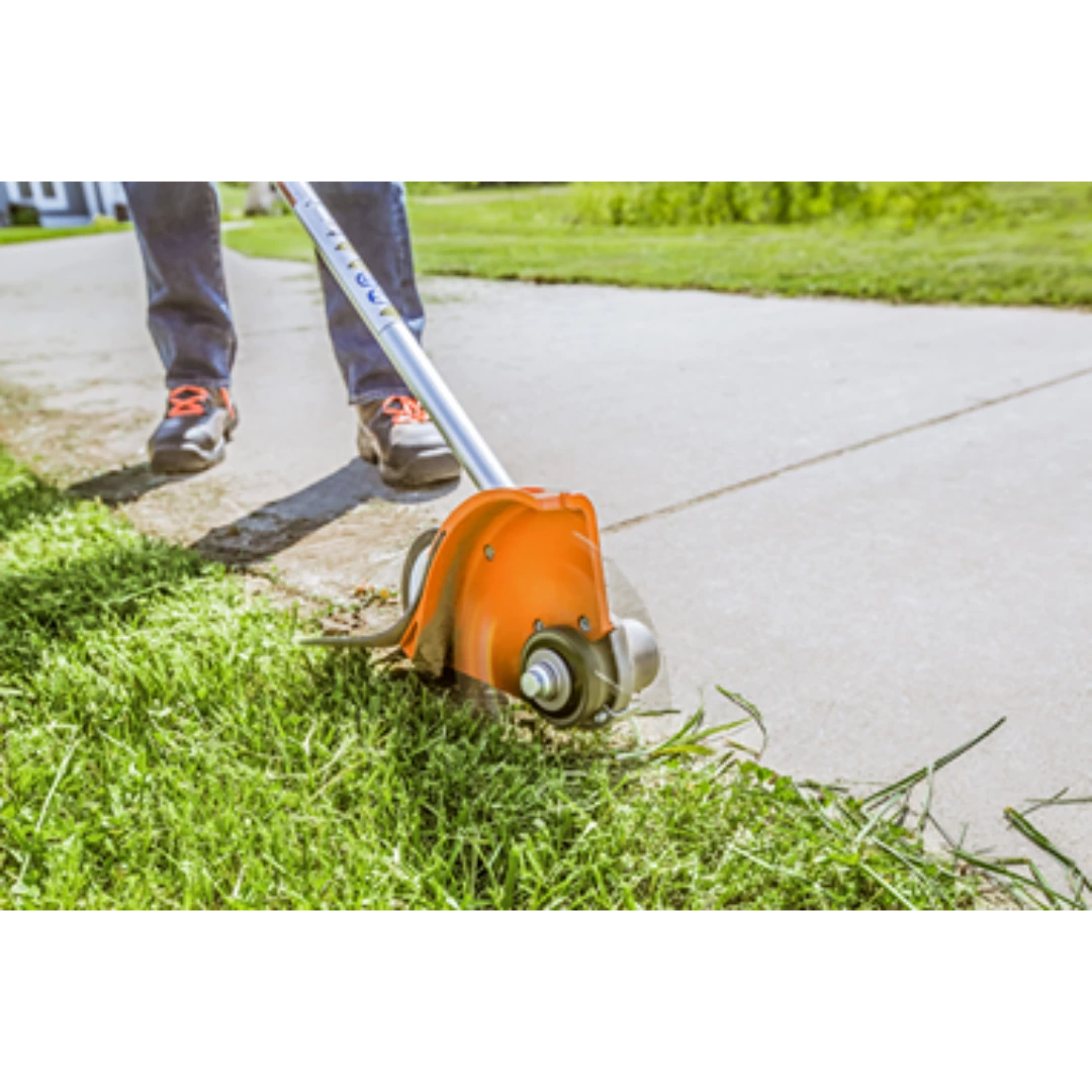 Professional-grade straight shaft edger with orange guard cutting grass along a concrete sidewalk for lawn care tasks