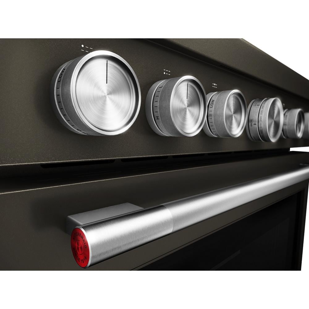 Close-up of stainless steel control knobs and handle on black KitchenAid dual fuel range from Ranges & Kitchenware collection