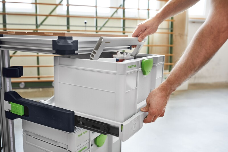 Hands sliding white and green Festool pull-out drawer into black rails of mobile workcenter for workshop organization