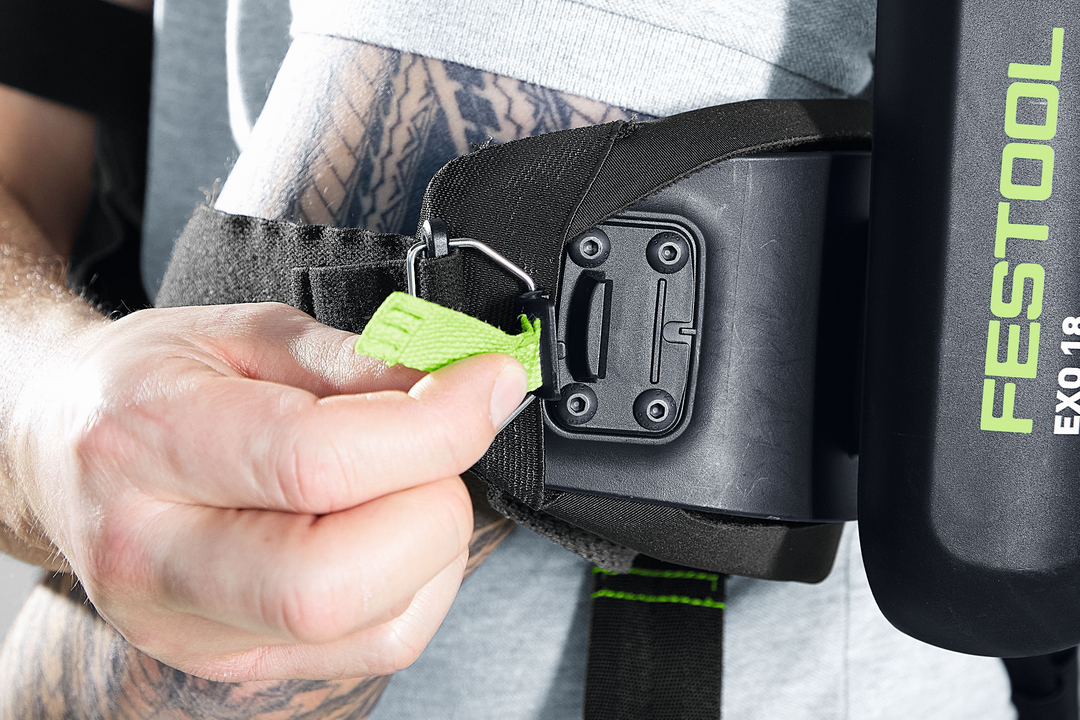 Close-up of hand adjusting green strap on black ergonomic support harness in Festool Power Tool Accessories collection
