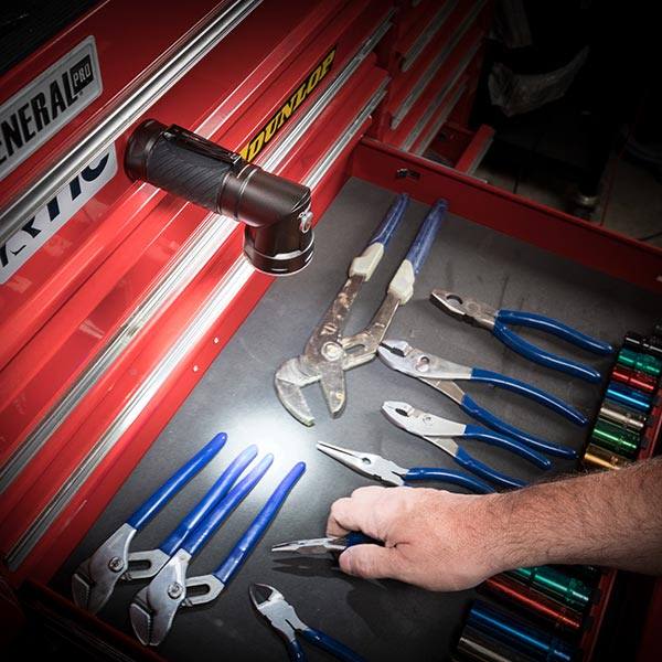 Rechargeable pivot light with magnetic base illuminating a toolbox drawer filled with hand tools for home improvement tasks