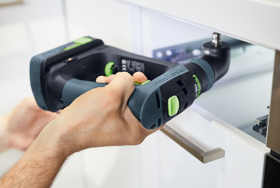 Hands using Festool 18V cordless drill with right-angle attachment for precise drilling in tight cabinet space