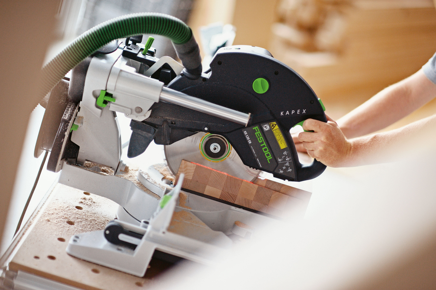 Person operating Festool sliding compound miter saw for precise woodworking in power tools and home improvement collection