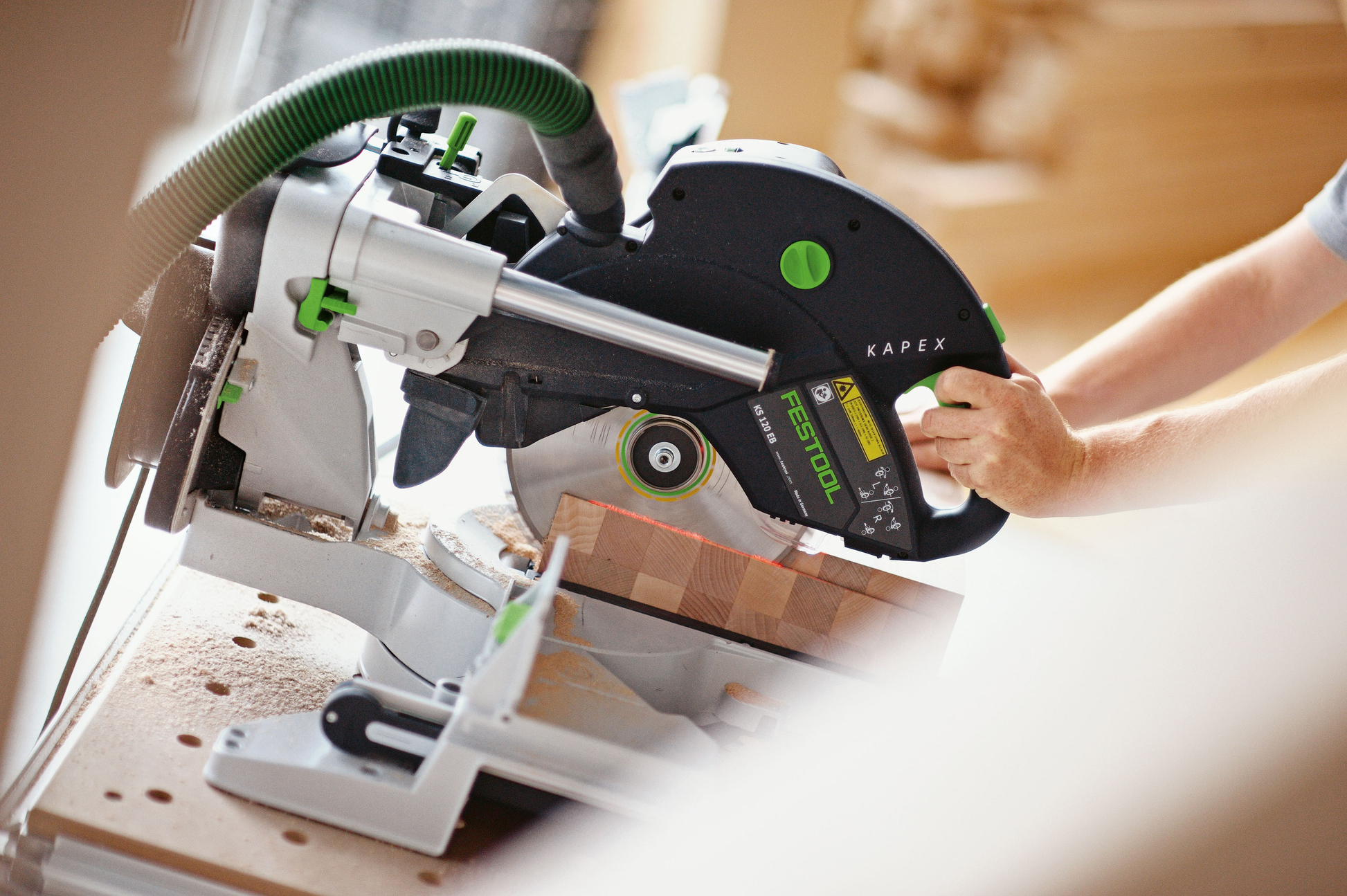 Person operating Festool sliding compound miter saw for precise woodworking in power tools and home improvement collection
