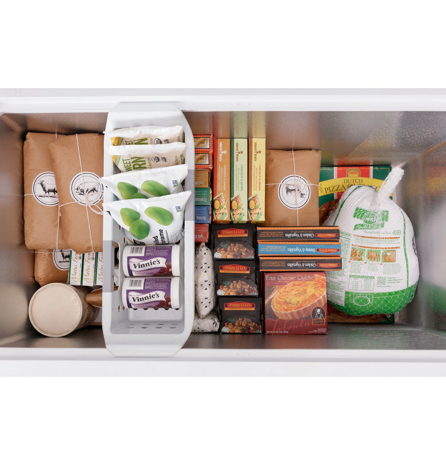 Interior of chest freezer neatly organized with frozen meats, packaged foods, frozen vegetables, and boxed meals inside metal compartment