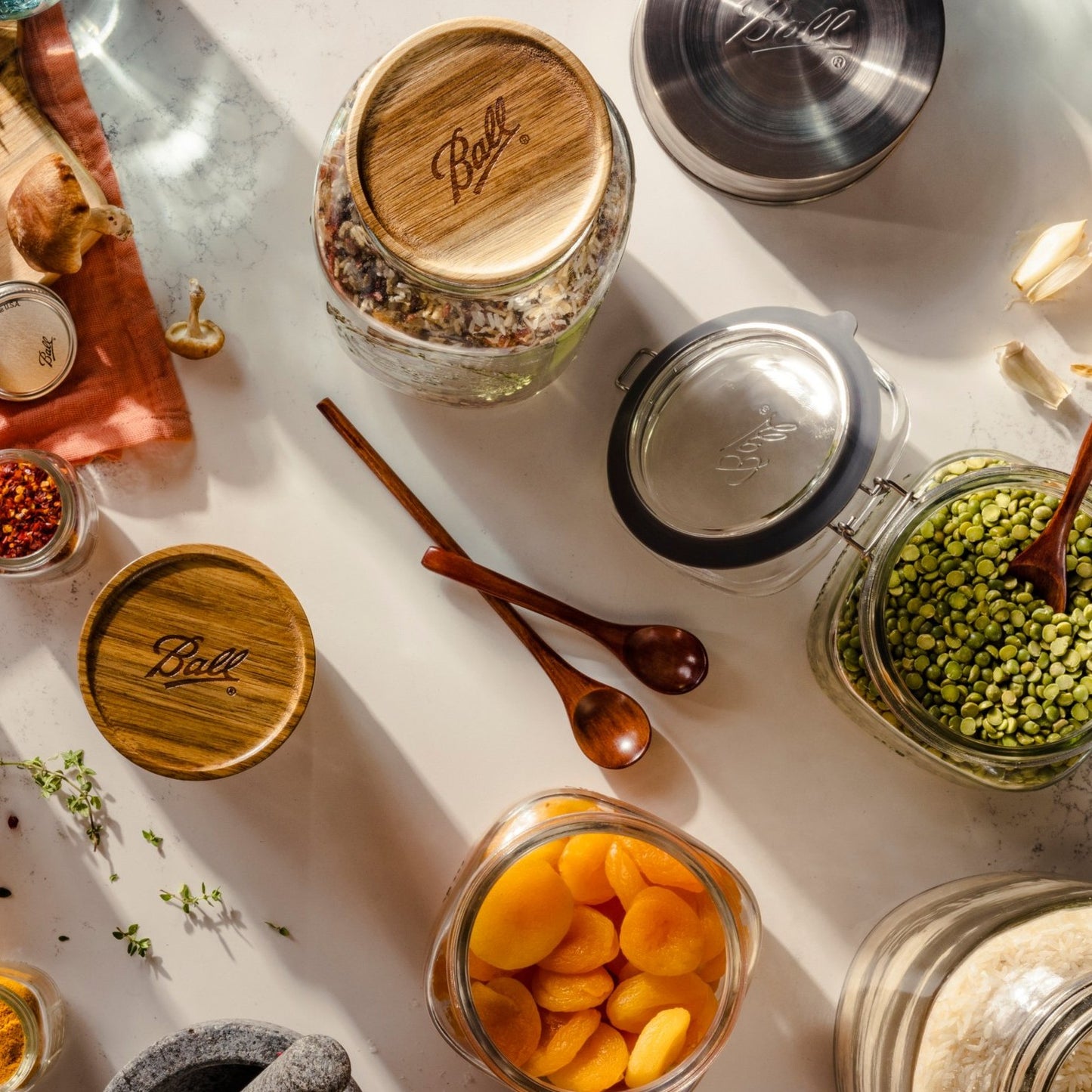 Three wooden jar lids with Ball logo on glass containers of dried goods on kitchenware countertop under $50 collection