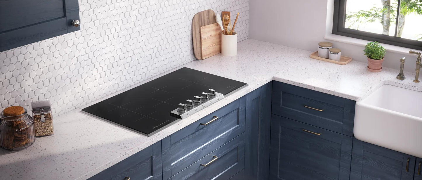 Modern kitchen with navy blue cabinetry and a sleek black induction cooktop integrated into a white speckled countertop