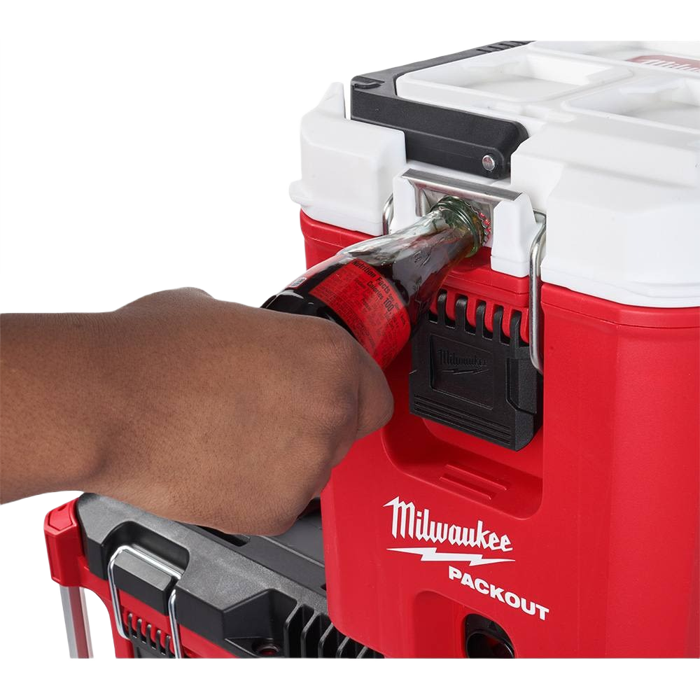 Hand opening a bottle with built-in opener on a red and white Milwaukee PACKOUT compact cooler for jobsite use