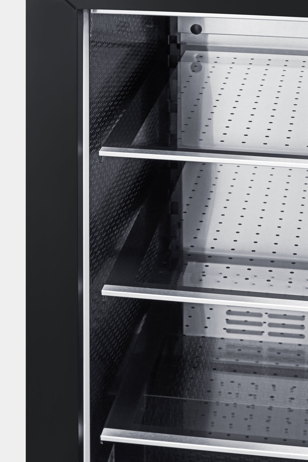 Close-up of beverage center interior with perforated metal shelves and textured black side panels in kitchen appliance setup