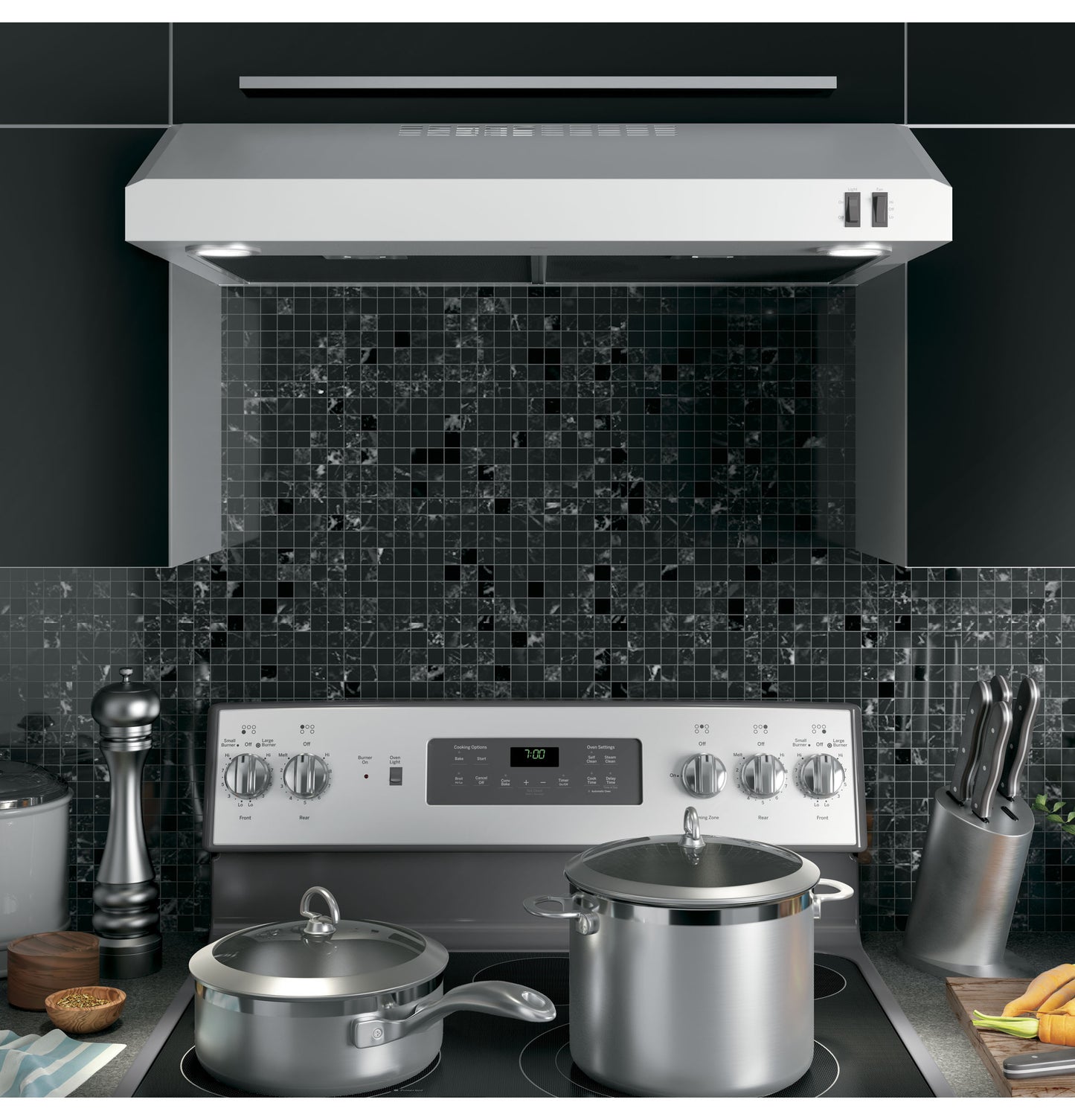 Stainless steel under cabinet range hood with dual vent controls and lighting over stovetop in kitchen appliances collection