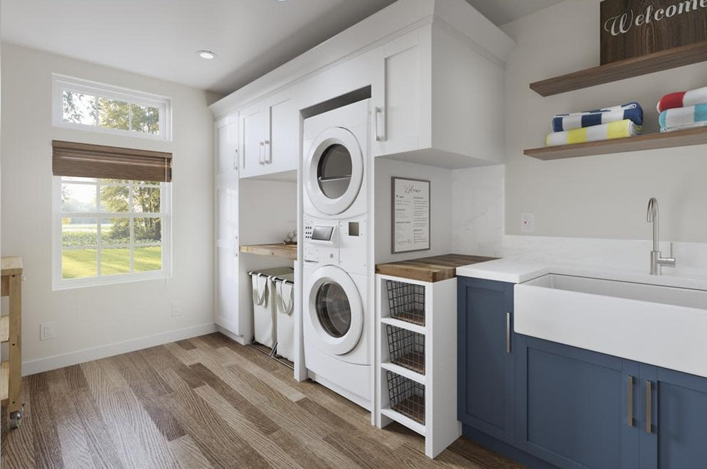 Stacked front load washer and dryer combo in bright laundry room with built-in cabinetry and wood flooring