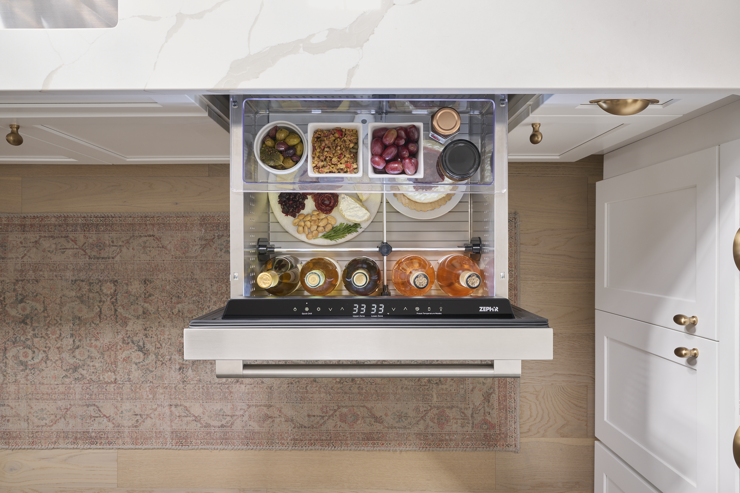 Under-counter stainless steel dual zone refrigerator drawer open with organized snacks and drinks in kitchenware collection